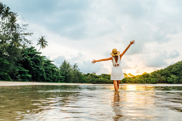 Young happy woman rising hands up enjoying beautiful sunset