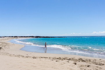 Fototapeta na wymiar Girl teen having fun at the empty beach in sunny weather . Crisis in turism. 