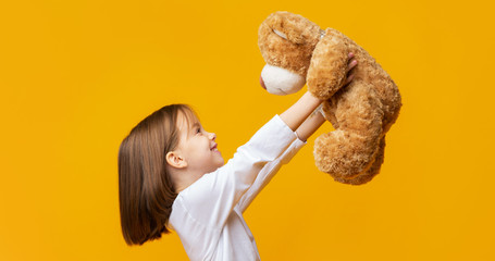 Cheerful girl holding big toy teddy bear