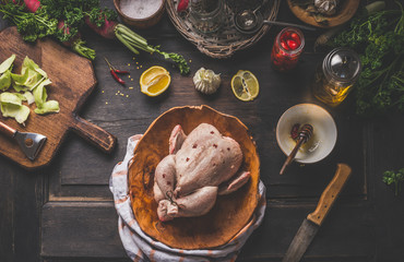 Raw whole chicken on dark rustic background with ingredients for tasty home cooking. Preparation and chicken marinating with lemon, honey and  mustard. Home cuisine. Top view