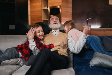 Grandfather and little grandchildren having fun together, shouting and laughing. Enjoying leisure...