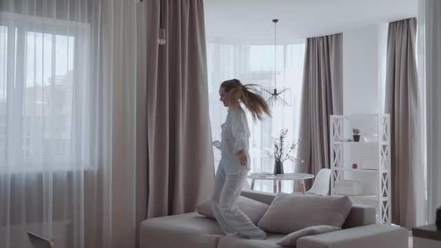 girl having fun and jumping on sofa In the interior of the apartments