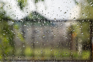 Raindrops on window pane. Blurred background outside the window in the rain.