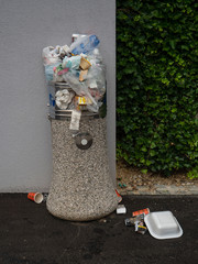VERTICAL: Inconsiderate people leave garbage on top and around overflowing bin.