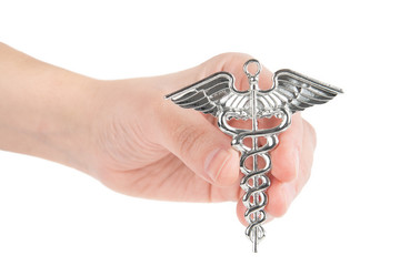 Female hand holds a two-snake design Hermes symbol. Caduceus as a symbol of medicine. Close-up...
