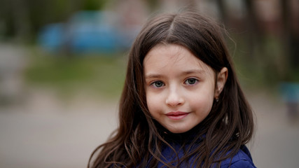 Portrait of a pretty little girl with long loose hair in a park
