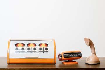 Classic telephone with orange table clock and retro patern bread box from circa 60s