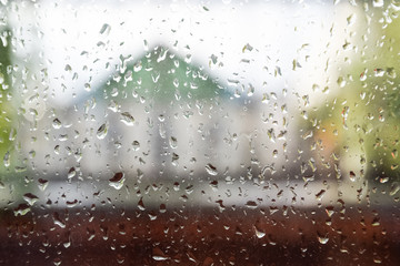 Raindrops on window pane. Blurred background outside the window in the rain.