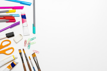Back to school background with accessories for the schoolroom - paints, pencils, notebooks, books, scissors, chalk, markers, white background, above copy space