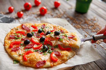 From above unrecognizable woman holding a piece of tasty pizza. Horizontal indoors shot.