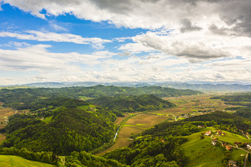 Obraz premium Aerial view of of green hills and vineyards with mountains in background