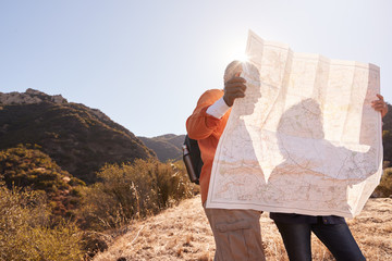 Senior Couple Looking At Map As They Hike Along Trail In Countryside Together