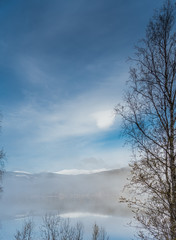 Widok na szczyt górski odbijający się w jeziorze w mglisty poranek w okolicach miejscowości Norfjell