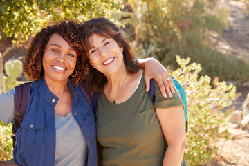 Portrait Of Two Senior Female Friends Hiking Along Trail In Countryside Together