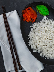 Closeup of rice and chopsticks on black background. Chinese dish. Vertical shot.