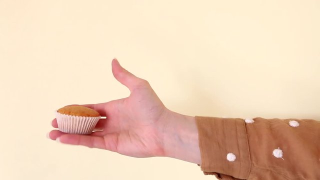 Woman is holding a singl cupcake in her hand.