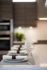 Simple and stylish dinner setting on sleek minimalist modern kitchen island with white countertop and dark cabinets