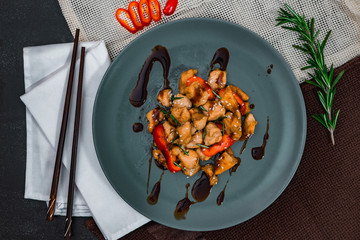 Chicken with soy sauce and chopsticks on blue plate. Chinese dish, spicy lunch.