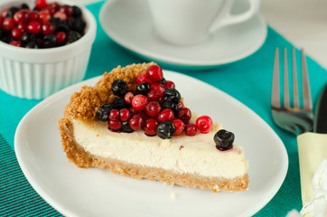 New York style Cheesecake on white plate decorated with fresh berries, on table with copy space so sweet and delicious. Homemade bakery concept.