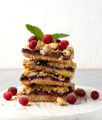 stack of square slices of baked crumble pie with blue plum on a white wooden board