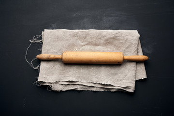 wooden rolling pin lie on a gray linen napkin, black table