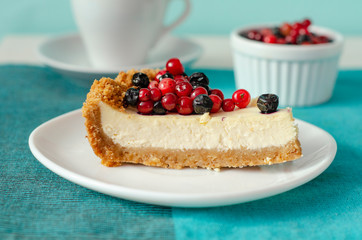 New York style Cheesecake on white plate decorated with fresh berries, on table with copy space so sweet and delicious. Homemade bakery concept.