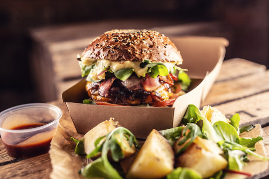 Tasty homemade burger takeaway in a box of recycled paper on wooden boards