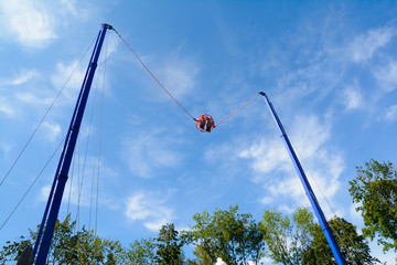 high bungee swing on the blue sky background in an amusement park
