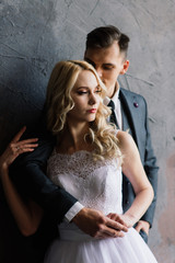 Cute wedding couple in the interior of a classic studio decorated. They kiss and hug each other.