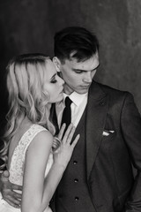 Cute wedding couple in the interior of a classic studio decorated. They kiss and hug each other.