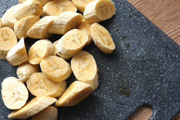 Pile of slices sweet banana above black cutting board