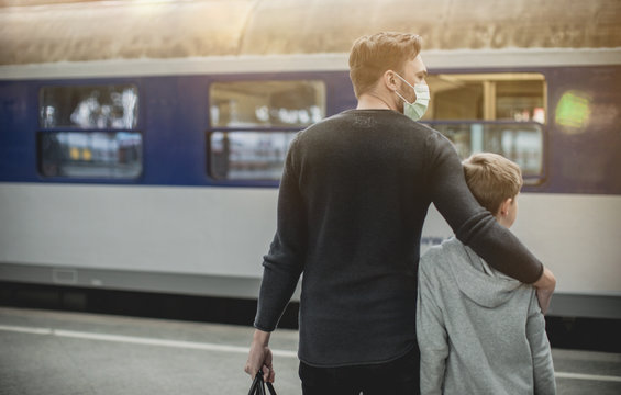 young family waiting for Train,
young father with son in front of train in train station wearing a face mask