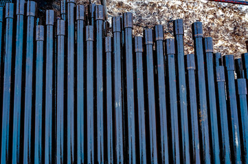 Obraz premium Oil Drill pipe. Rusty drill pipes were drilled in the well section. Downhole drilling rig. Laying the pipe on the deck. View of the shell of drill pipes laid in courtyard of the oil and gas warehouse