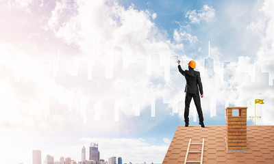 Man architect draw silhouette of modern city on blue sky. Mixed media