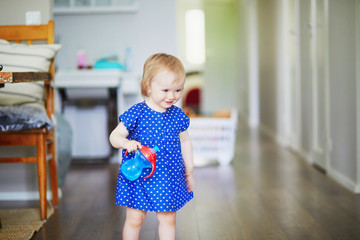 Fototapeta premium Baby girl in blue dress putting her water bottle on the table