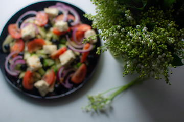 lilies of the valley in a vase on a table on a background of salad