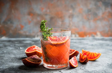 Old-fashioned cocktail with blood oranges and thyme on the rustic background. Selective focus. Shallow depth of field.
