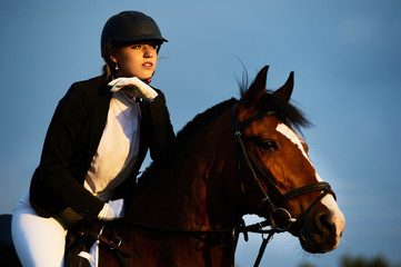 Girl equestrian rider riding a beautiful horse  in the rays of the setting sun. Horse theme