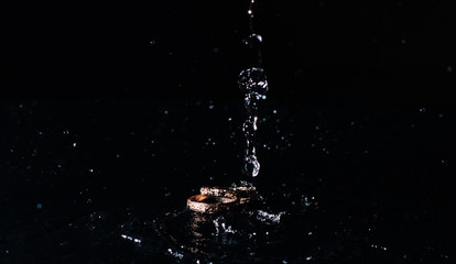 wedding rings with the water splash on black background