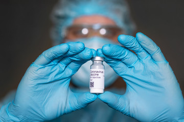 Coronavirus vaccine. Doctor with a vaccine. Hands holding a coronavirus vaccine ampoule, Covid-19