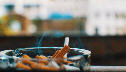 ashtray full of cigarettes smoking with blurry background