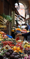 Fototapeta na wymiar Frutería en mercado callejero de Bologna (Emilia Romagna, Italia) Mujer escoge tomates