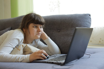 Caucasian girl laying on the sofa with laptop,lockdown at home during coronavirus