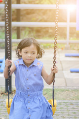 The girls play on the playground sit on the swing with fun and happiness.