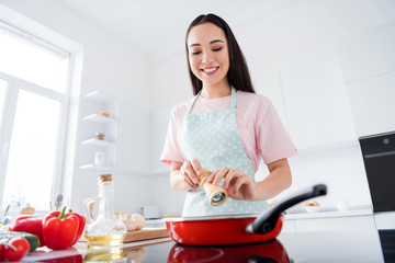 Portrait of her she nice attractive lovely focused busy cheerful careful housewife making delicious meal lunch adding spices weight loss lifestyle in modern white light interior style kitchen
