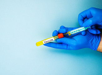 hands in blue medical gloves fill a syringe with the covid-19 coronavirus vaccine, a cure for viral...
