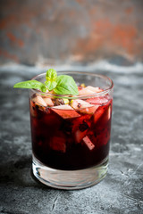 Old fashioned cocktail with blackberry liqueur and apple slices on rustic background. Selective focus. Shallow depth of field.
