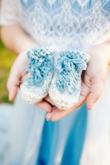 Baby's blue handmade bootees in mum's hands, close up.