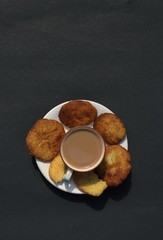 Top View of Tea Cup and Homemade Semolina Cookies in a Plate Isolated on Black Background with Copy Space in Vertical Orientation 