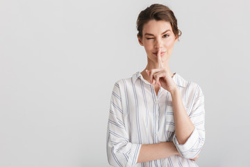 Image of pleased nice woman showing silence gesture and winking